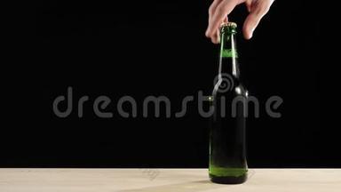新<strong>鲜啤酒</strong>。 手拿一个绿色的瓶子和美味的工艺<strong>啤酒</strong>从木桌上黑色背景。 冷<strong>鲜啤酒</strong>